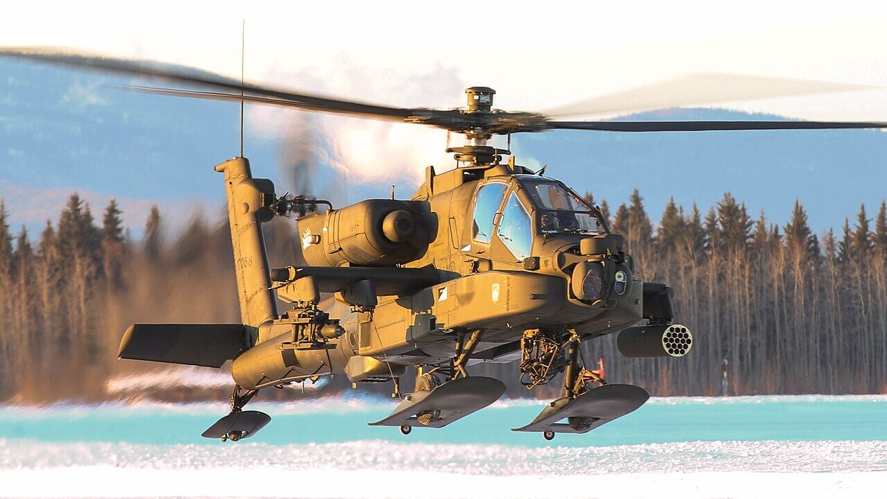 AH-64 Apache helicopter in flight over snowy terrain