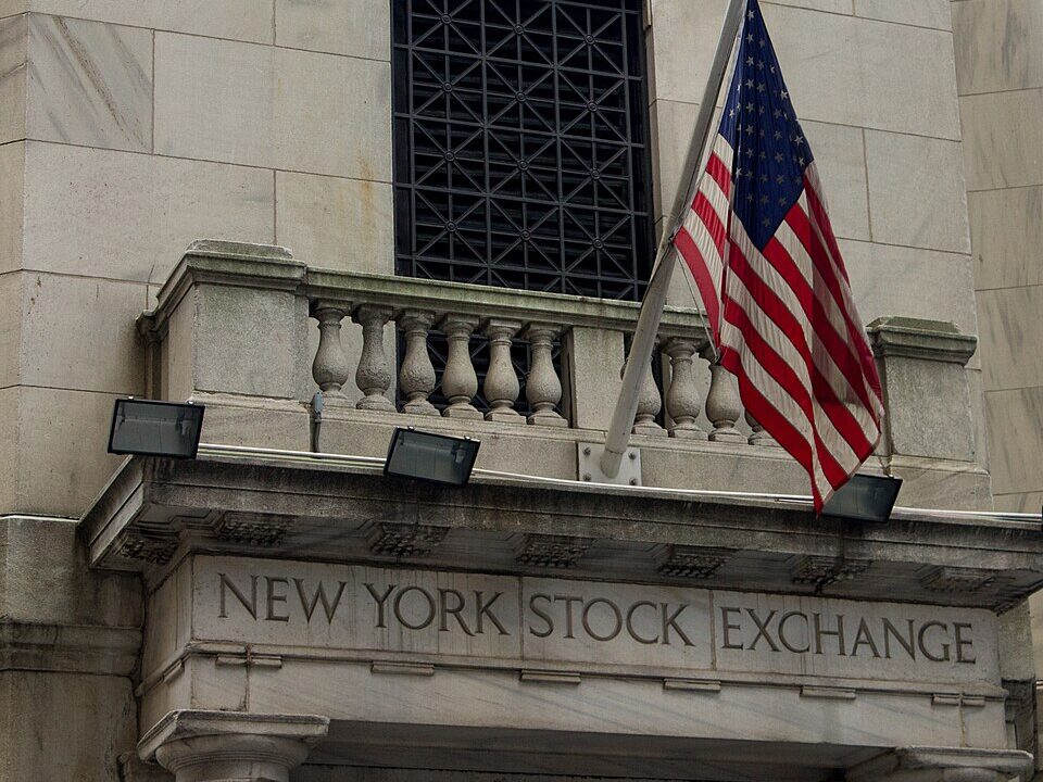 Stone entrance of the New York Stock Exchange with a US flag above it