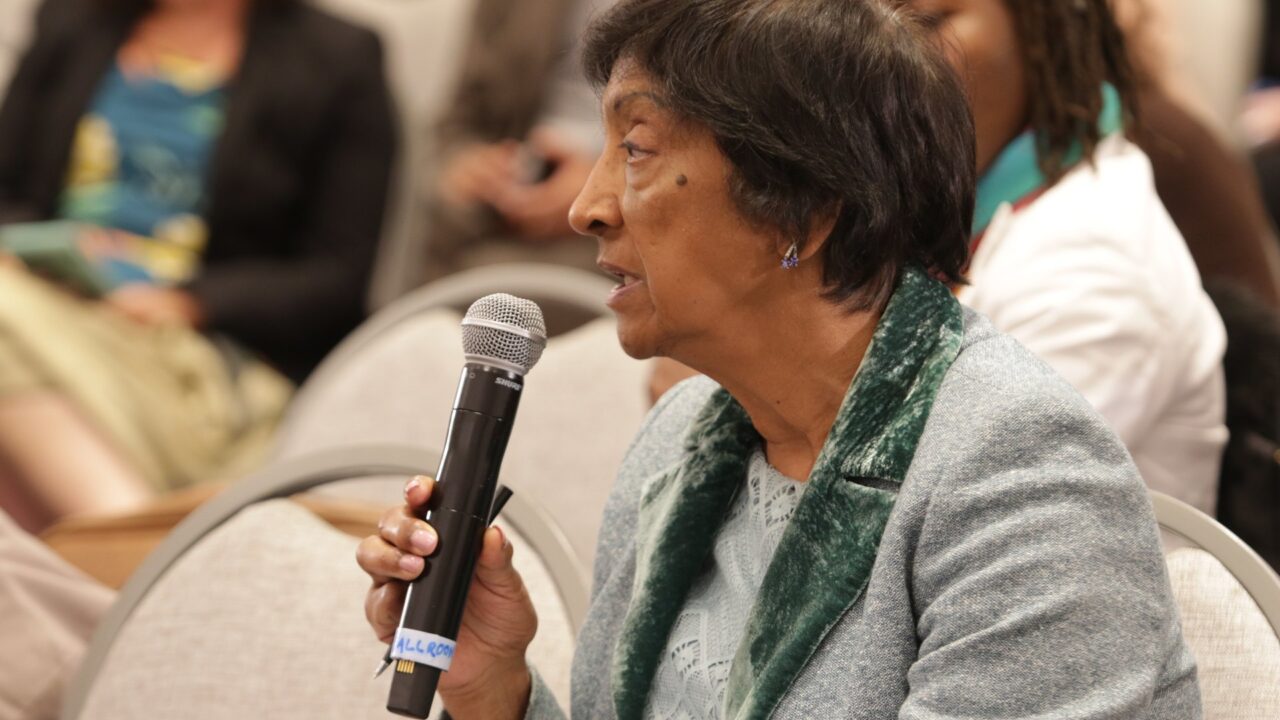 Navi Pillay holding a microphone while speaking at a conference