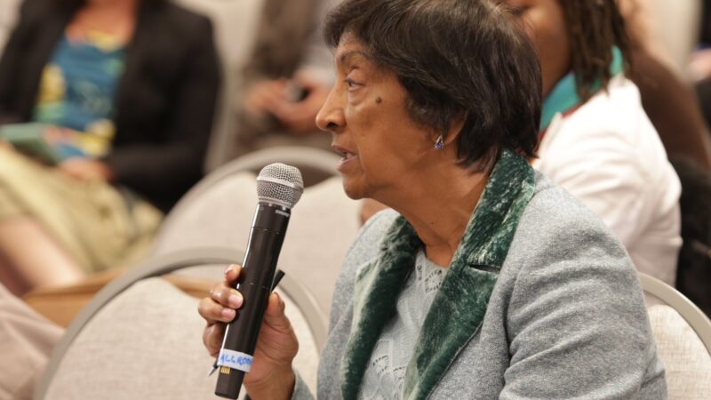 Navi Pillay holding a microphone while speaking at a conference