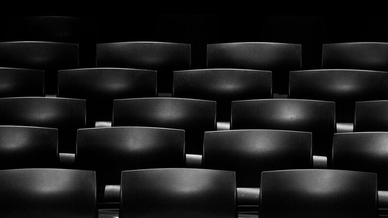 Rows of empty dark cinema seats photographed inside a movie theatre